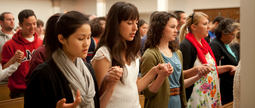 Students in mass holding hands in prayer.