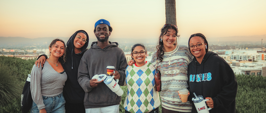 Image of students standing on the LMU bluff with a view of the city behind them.