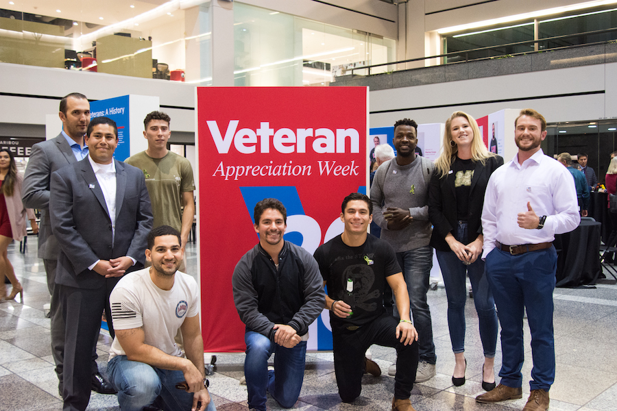 Veteran students standing together in a group, posing in front of a banner that says 