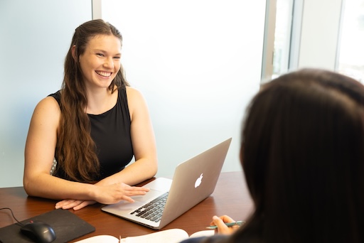 Student in a staff member's office discussing resources. Student is sitting directly across the staff member with a laptop in between them.