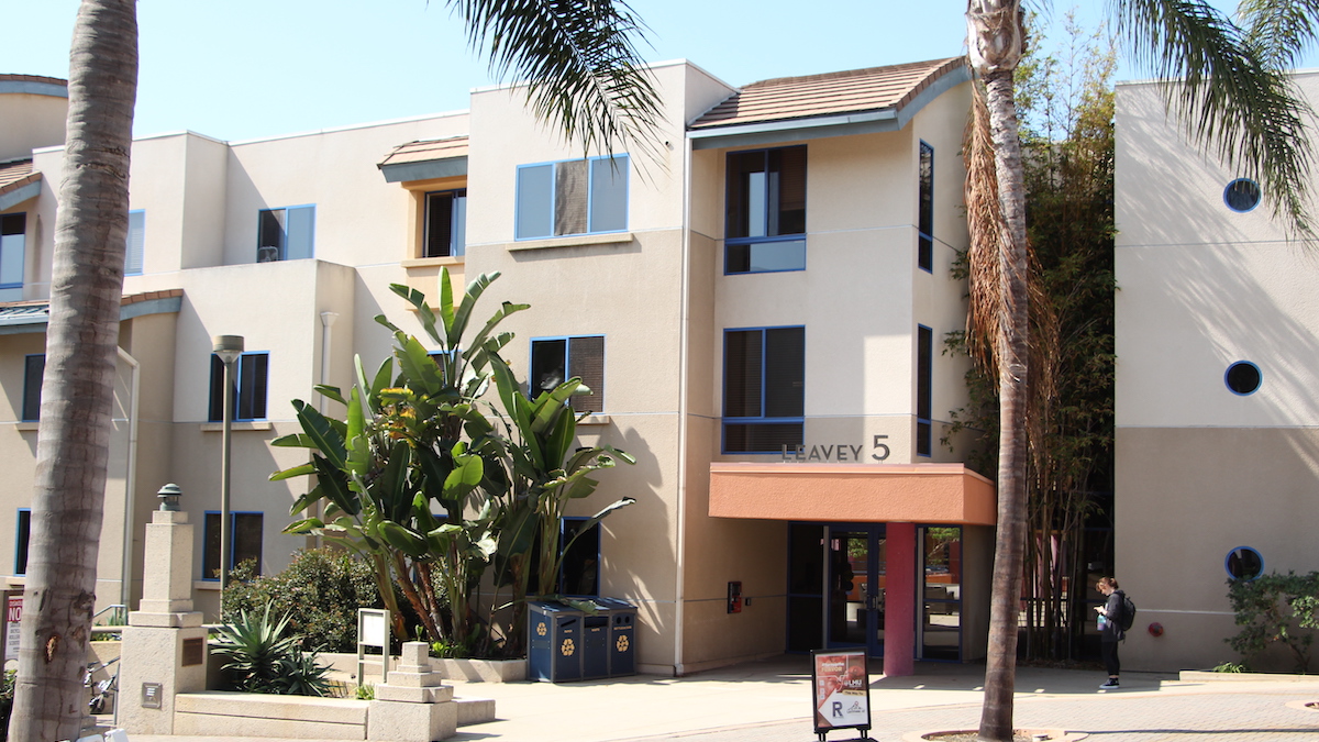 View of Leavey 5 from the exterior. Windows are visible on the building and a girl waits by the door.